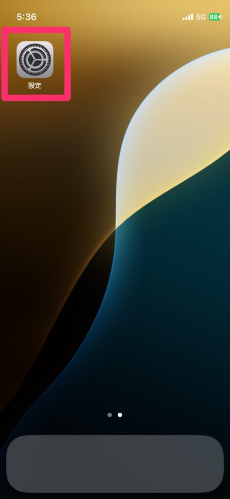 iPhoneのホーム画面から設定アプリをタップして開く手順を示したスクリーンショットの画像